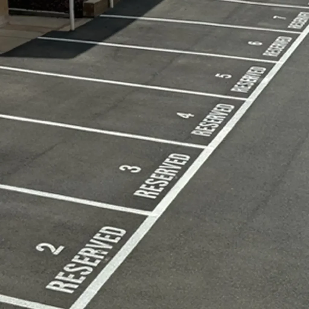 A row of empty parking spaces, each marked with a white number and the word "RESERVED" on the asphalt, numbered 2 through 7.